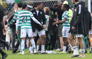 Celtic players celebrate with our fans on the pitch at Ibrox.